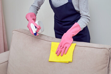 The girl in rubber gloves scans the detergent on the furniture. Without a face.