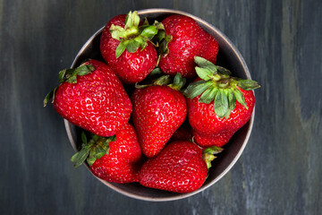bowl with healthy strawberries, grouped in the middle on a dark table