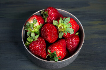 bowl with healthy strawberries, grouped in the middle on a dark table