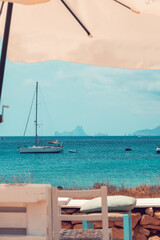 Impressive view of the turquoise sea and crystal clear water on the beach of Ses Illetes in Formentera Island, one of the Balearic Islands, from a typical chiringuito bar. Mediterranean summer.