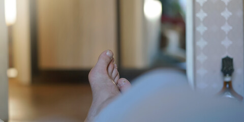 man bare feet look out of blanket against blurry room