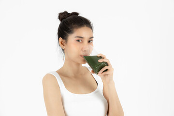 Healthy young Asian woman drinking green detox vegetable smoothie over white isolated background. Vegetarian drink juice, Healthy lifestyle, Fitness and health care concept.