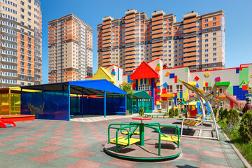 The playground in the courtyard of a new kindergarten with new residential buildings in the background
