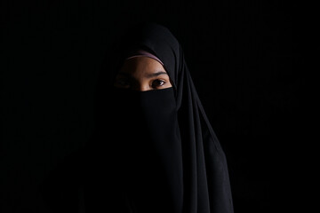 Naklejka premium Portrait of Beautiful Muslim Woman in niqab on black background