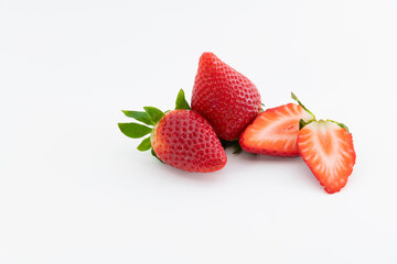 two fresh whole strawberries next to a strawberry cut in half. Healthy and vegan food concept.