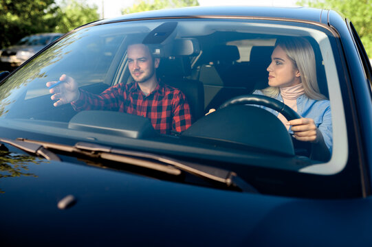 Lady and male instructor in car, driving school