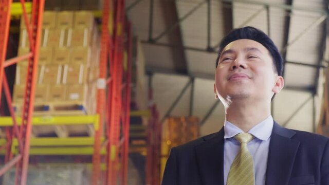 Asian male business owner in suit walking in warehouse factory