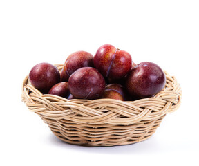 Plums in basket on white background. Fresh plums in a wicker basket on white background. Plums fruit heap in basket on white background