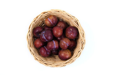 Obraz premium Plums in basket on white background. High angle view of fresh plums. Top view of plums fruit on white background.