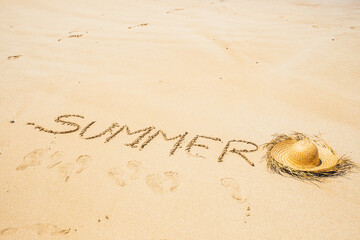 Summer holiday vacation at the beach concept for tourist and tourism - words wrote on the sand at the beach and sun hat on the ground - footprints around