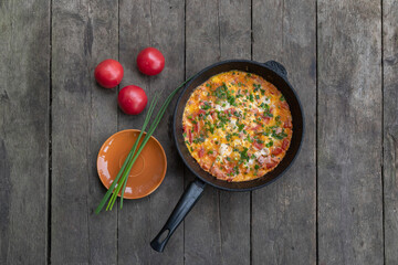 frying pan with an omelette on a wooden dark background. View from above