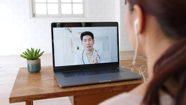 Asian woman talking with doctor via computer laptop virtual video call or video conference at home, telehealth and telemedicine concept