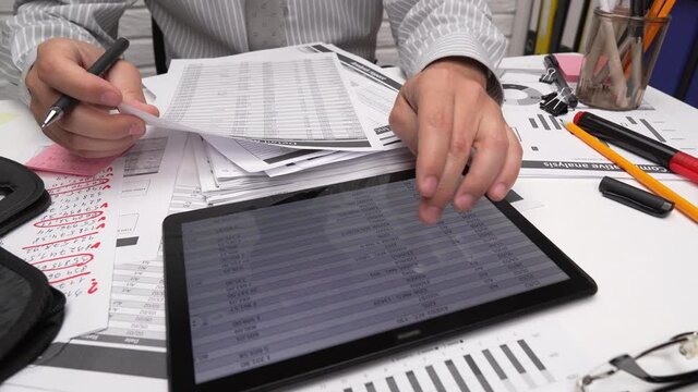 Business analysis and accounting concept - businessman working with document, spreadsheet, using calculator, tablet pc. Office desk closeup. 
