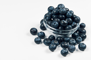 Freshly juicy picked blueberries in glass bowl isolated on white background. Top view. Selective focus. 
