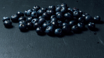 Freshly juicy picked blueberries on dark background. Selective focus. Free text space. 