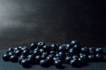 Freshly juicy picked blueberries on dark background. Selective focus. Free text space. 