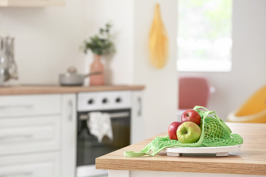Shopping bag with fresh apples on table in kitchen