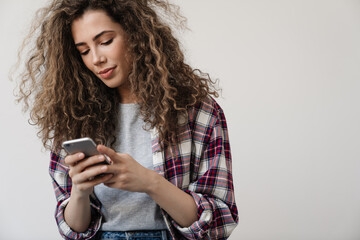 Photo of pleased beautiful woman using cellphone while posing on camera