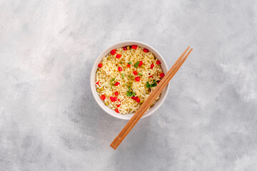 Instant noodle with pepper,peas and greens. Gray stone background top view copy space