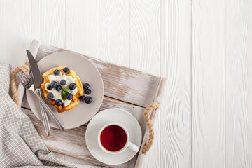 Breakfast on Belgian waffles on served table on white wood background top view