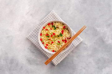 Instant noodle with pepper,peas and greens. Gray stone background top view copy space
