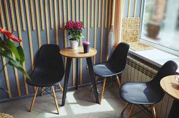 Interior of modern cafe. Disposable coffee paper cup on table. Coffee shop, cafe