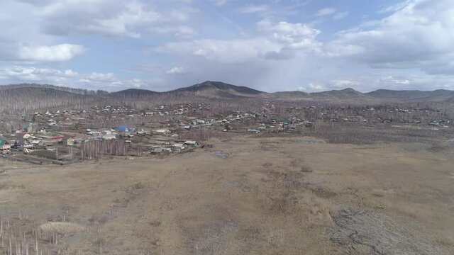 Aerial view of Karabash city with private houses. Empty streets. Spring, trees without leaves. At the background the Ural mountains. Russia, Chelyabinsk region
