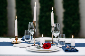 Table setting, wineglasses, candles and flower