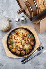 Directly above photo of baked potatoes with chicken on a grey pub table, baked and served in cast iron skillet