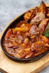 Close up of meat and potato ragout in red sauce in cast-iron skillet