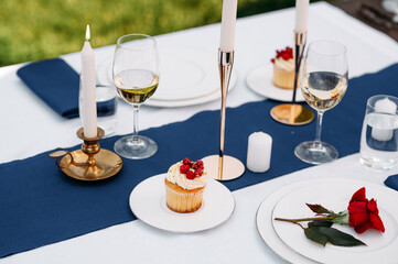 Table setting, glasses, candles, flower and sweets