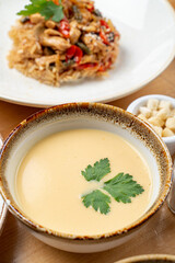Creamy pumpkin soup with a leaf of parsley close up on wooden table