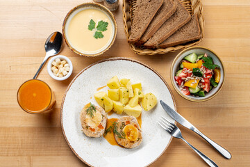Lunch in a restaurant with chicken cutlets, mashed potato, soup and bread basket, directly above menu photo