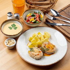 Whole lunch in a restaurant: summer salad, cream soup, meat with potato and fruit drink