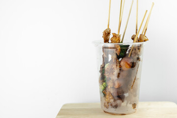 Picture of grilled pork with spicy hot Szechuan pepper sauce in plastic glasses, local street food and spicy Thai style food