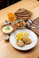 Whole lunch in a restaurant: summer salad, cream soup, meat with potato and fruit drink
