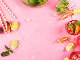 Pink background with ingredients for summer iced red cocktail with blood orange and lime