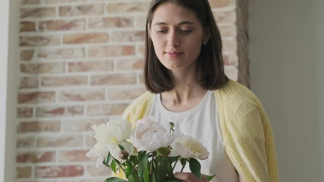 Young amazing cute woman indoors at home with beautiful flowers