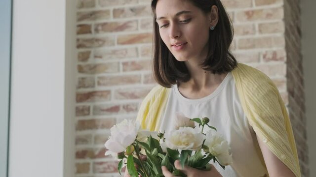 Young pleased optimistic cute woman indoors at home with beautiful flowers