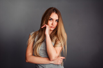 A girl with blue eyes looks piercingly into the frame, wrapping her hair in a gray background