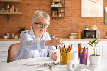 Senior woman coloring picture in kitchen