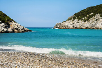 Light surf on the Glisteri beach of Skopelos in summer with clear blue sea.