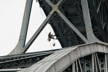 Painter working on the Porto Bridge. A worker repairs the Porto bridge hanging by ropes