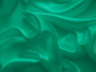 Beautiful elegant wavy emerald green satin silk luxury cloth fabric texture, abstract background design. Card or banner.