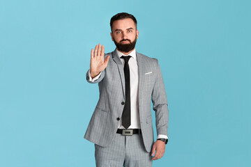 Expressing rejection. Confident entrepreneur in formalwear showing STOP gesture over blue background