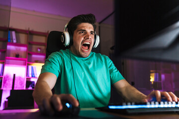 Image of shocked young man screaming while playing video game