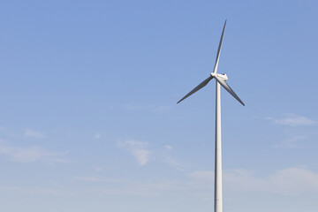 Wind turbine on the green grass over the blue clouded sky. Protection of nature. Wind turbine - renewable energy source.