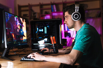 Image of caucasian focused man playing video game on computer