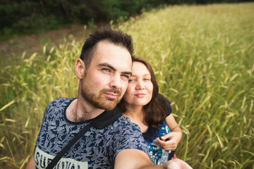 Travel, vacation and holiday concept - Happy caucasian couple taking selfie against background on the wheat field