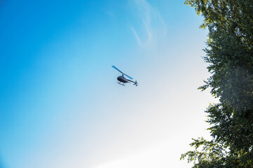 Fototapeta na wymiar Miniature black helicopter in the sky over forest on a sunny day.